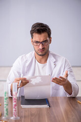 Young male chemist in front of white board
