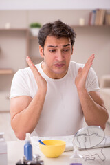 Young man shaving face at home