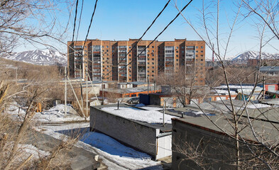 Fototapeta na wymiar Modern apartment building. Garage cooperative. Factory chimney. Spring. Blue sky. White snow. Ust-Kamenogorsk (kazakhstan)