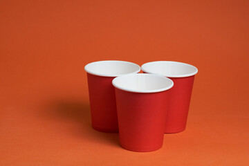 Three red disposable cups on a brown background. Place for text