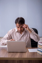 Young male teacher sitting in the classroom