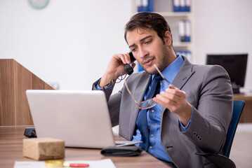 Young male employee talking by phone