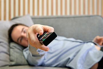 Men with the remote control, front of the television. Switching channels.