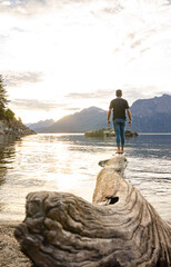 persona sobre un árbol al borde del agua de un lago en la Patagonia Argentina al atardecer con montañas de fondo mirando el paisaje