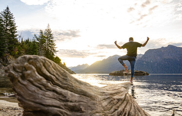 persona sobre un árbol al borde del agua de un lago en la Patagonia Argentina al atardecer con montañas de fondo mirando el paisaje
