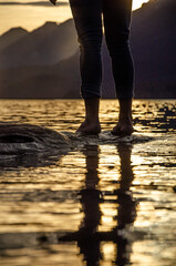 pies de una persona sobre un árbol al borde del agua de un lago en la Patagonia Argentina al atardecer con montañas de fondo