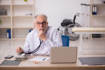 Old male doctor working in the clinic