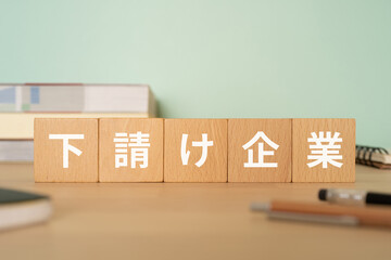 下請け企業と書かれたブロックが置かれたデスク