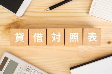 貸借対照表と書かれたブロック、電卓、スマホ、ノート、カレンダー