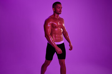 Man athletic bodybuilder poses with nude torso abs in full-length background, boxing and martial arts. Advertising, sports, active lifestyle, color light, competition, challenge concept. 