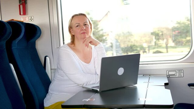 woman on train working on computer freelance work no rest woman contemplating fixing her hair focused online work