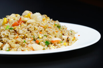 A plate of seafood scary Yangzhou fried rice on black background