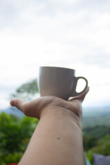hand holding cup of hot coffee with a view of the landscapes of colombia
