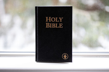 Religious book holy bible hardback black standing window sill help guidance god belief 