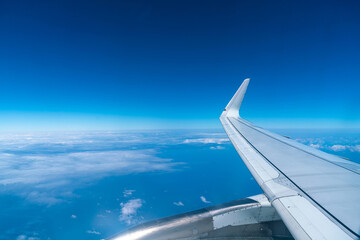 Obraz premium View of the blue sky and fluffy clouds from the window of the plane.