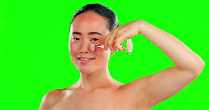Face, skincare smile and Asian woman with roller on green screen in studio isolated on background. Portrait, beauty dermatology and happy female model with rose quartz for healthy facial skin massage