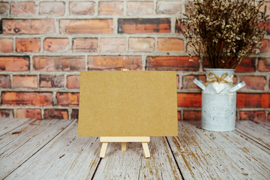 Mock up empty blank paper card on wooden easel with dried flowers bouquet