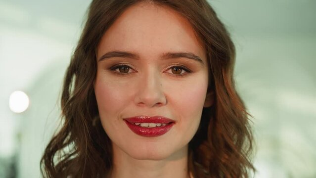 Happy woman with bright lip gloss looks in camera smiling