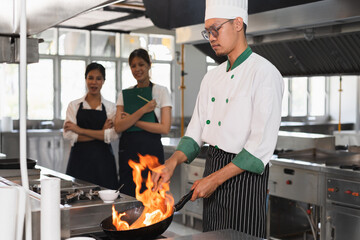 Asia chef cooking and teaching Asia woman assistant chef cooking at kitchen background	