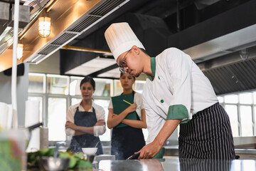Asia chef cooking and teaching Asia woman assistant chef cooking at kitchen background	