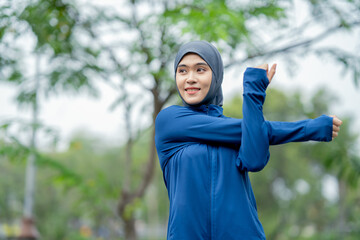 Asian cute muslim woman wearing sportswear and a blue hijab Exercising and running outdoors at the park in the morning. with a fresh feeling.