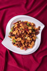 wok fried chicken cube meat with spicy hot dry chilli in Szechuan style on red white cloth asian...