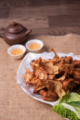 deep fried crispy golden chicken meat with ginger slices and garlic on wood table chinese tea pot asian halal banquet menu