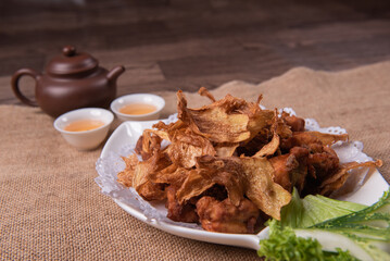 deep fried crispy golden chicken meat with ginger slices and garlic on wood table chinese tea pot asian halal banquet menu