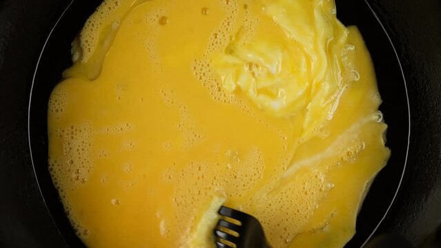 Mixing eggs in pan with fork. Cooking scramble eggs, omelette for breakfast
