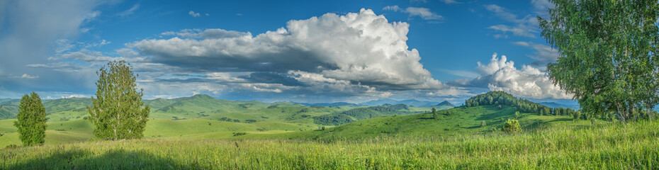 Panoramic view of a summer day in the mountains, green meadows, mountain slopes and hills, countryside