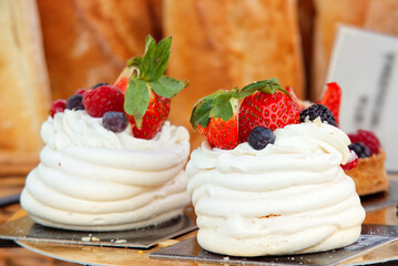 Pavlova desserts embellished with summer berries fruit, raspberries, strawberries, blueberries and currant. Closeup of the dessert at the stall at Prague farmers street food market.
