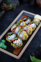 Rolls in tempura. Traditional Japanese cuisine. Ebi tempura. White ginger. Vertical photo on a black background with smoke.View from above.