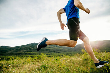 close-up athlete runner running on summer mountain plateau in sunset