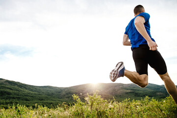 male runner running cross-country running race, colorful mountain plateau, summer sunset