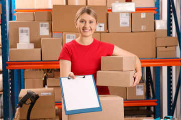 Post office worker with parcels and clipboard near rack indoors