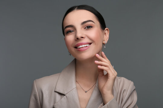 Young woman with elegant jewelry on dark grey background