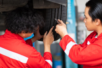 Mechanic checking checking the depth of car tire tread.  Car maintenance and auto service garage...