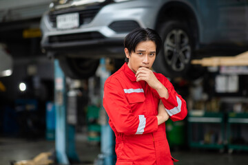 Portrait of a Asian mechanic working in his car service garage. Car maintenance and auto service garage concept.