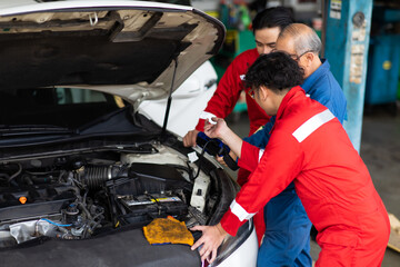 Professional team mechanic car repair service and checking car engine by Diagnostics Software computer. Expertise mechanic working in automobile repair garage.