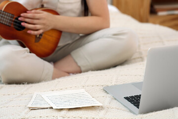 Woman learning to play ukulele with online music course at home, closeup. Time for hobby