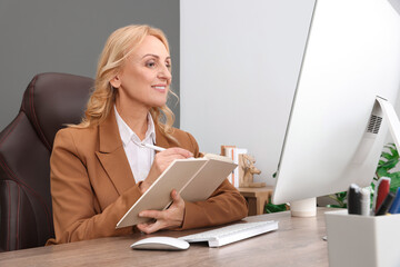 Lady boss working near computer at desk in office. Successful businesswoman