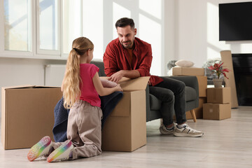 Family settling into home. Happy father and daughter unpacking boxes in new apartment. Moving day