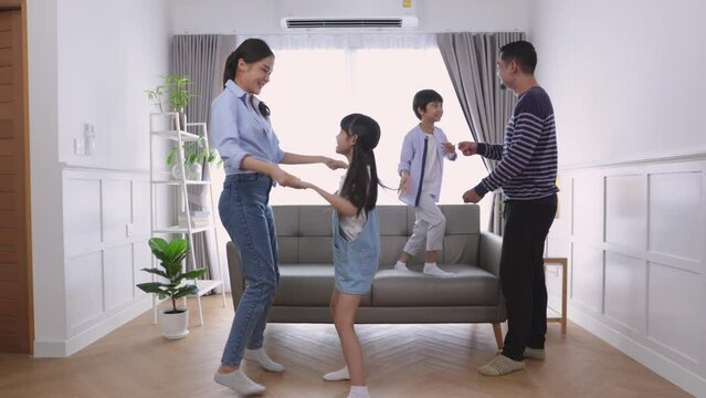 Asian family father mother and daughter jump dance cheerful moving together in  living room enjoying leisure lifestyle at home together.