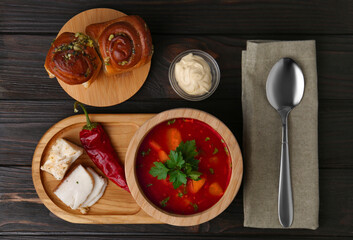 Delicious borsch served with pampushky and salo on wooden table, flat lay. Traditional Ukrainian cuisine