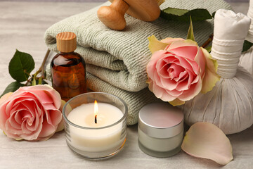 Fototapeta na wymiar Composition with spa products, roses and candle on grey wooden table