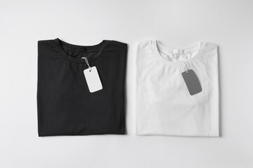 Stylish T-shirts with labels on white background, top view