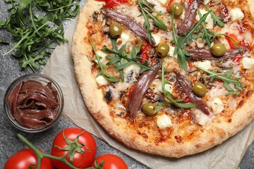 Tasty pizza with anchovies and ingredients on grey table, flat lay