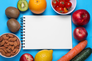 Notebook, almonds, fresh fruits and vegetables on light blue background, flat lay. Low glycemic index diet