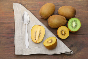 Many fresh kiwis and spoon on wooden table, above view