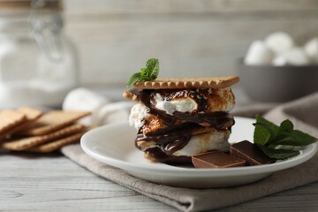 Delicious marshmallow sandwich with cracker and chocolate on white wooden table, closeup. Space for text